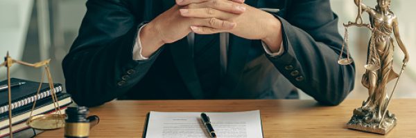 Concepts of justice and lawyers discuss contract paperwork with brass scales on a table with a judge's hammer placed in front of lawyers in the office. Legal, advice, justice, and conceptual services.